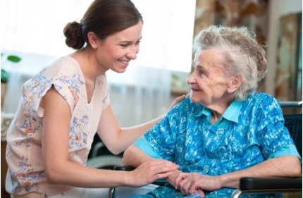 A caregiver sitting and holding hands with an older woman