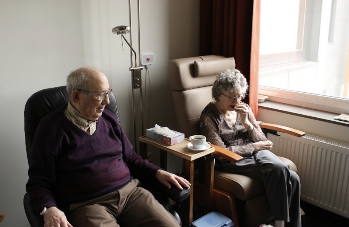 Two seniors talking together in a sunlit St. Louis living room during a companionship care visit