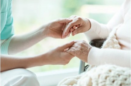 Hands gently holding the hands of an elderly person