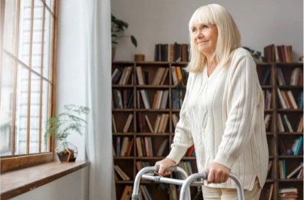 An older woman walking with a rolling walker at home